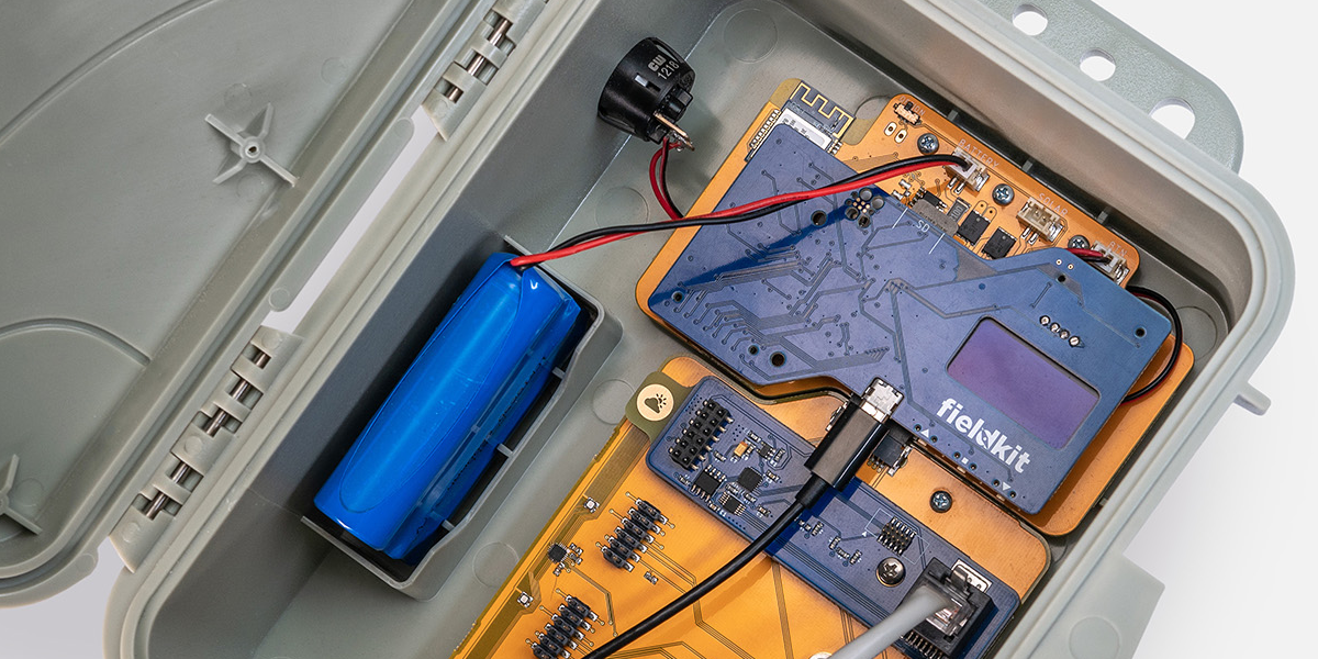 Closeup image of interior of FeildKit enclosure, showing micro USB plugged in and battery pack in addition to the boards